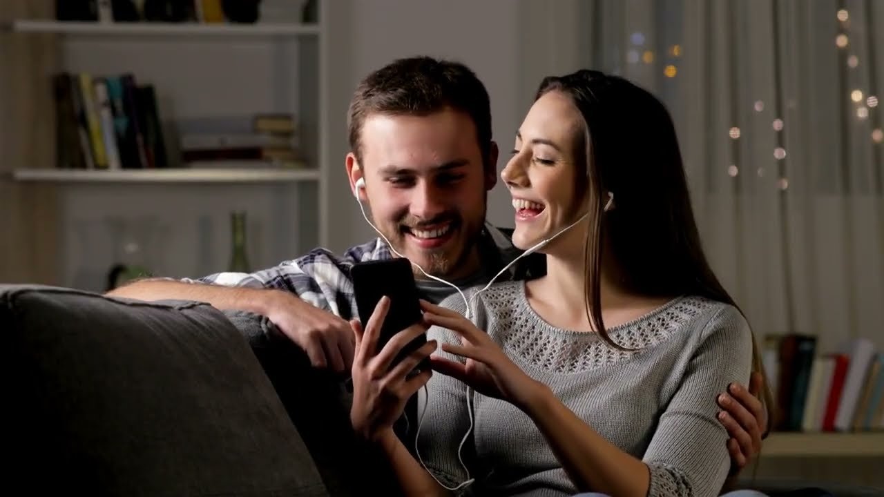 Young couple sharing headphones and listening to a custom song together